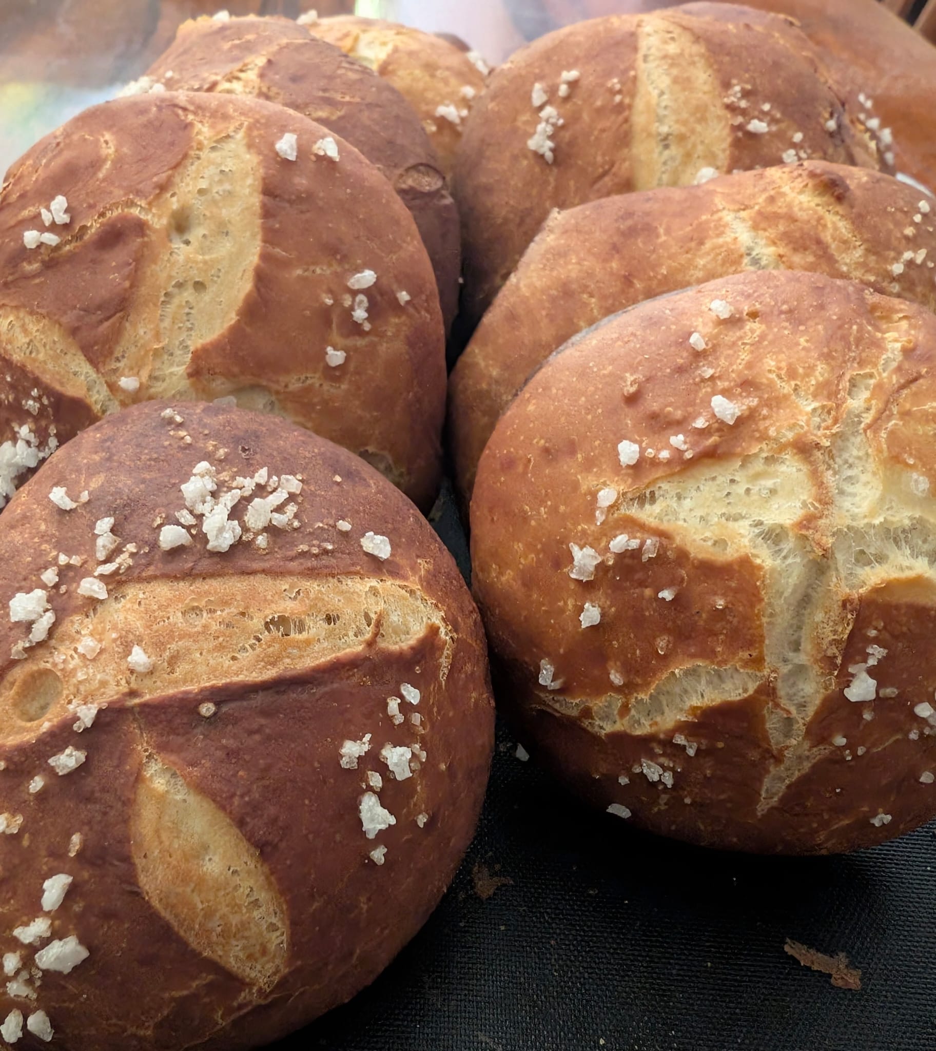 Close-up of golden bread rolls with scored tops and flakes of salt.